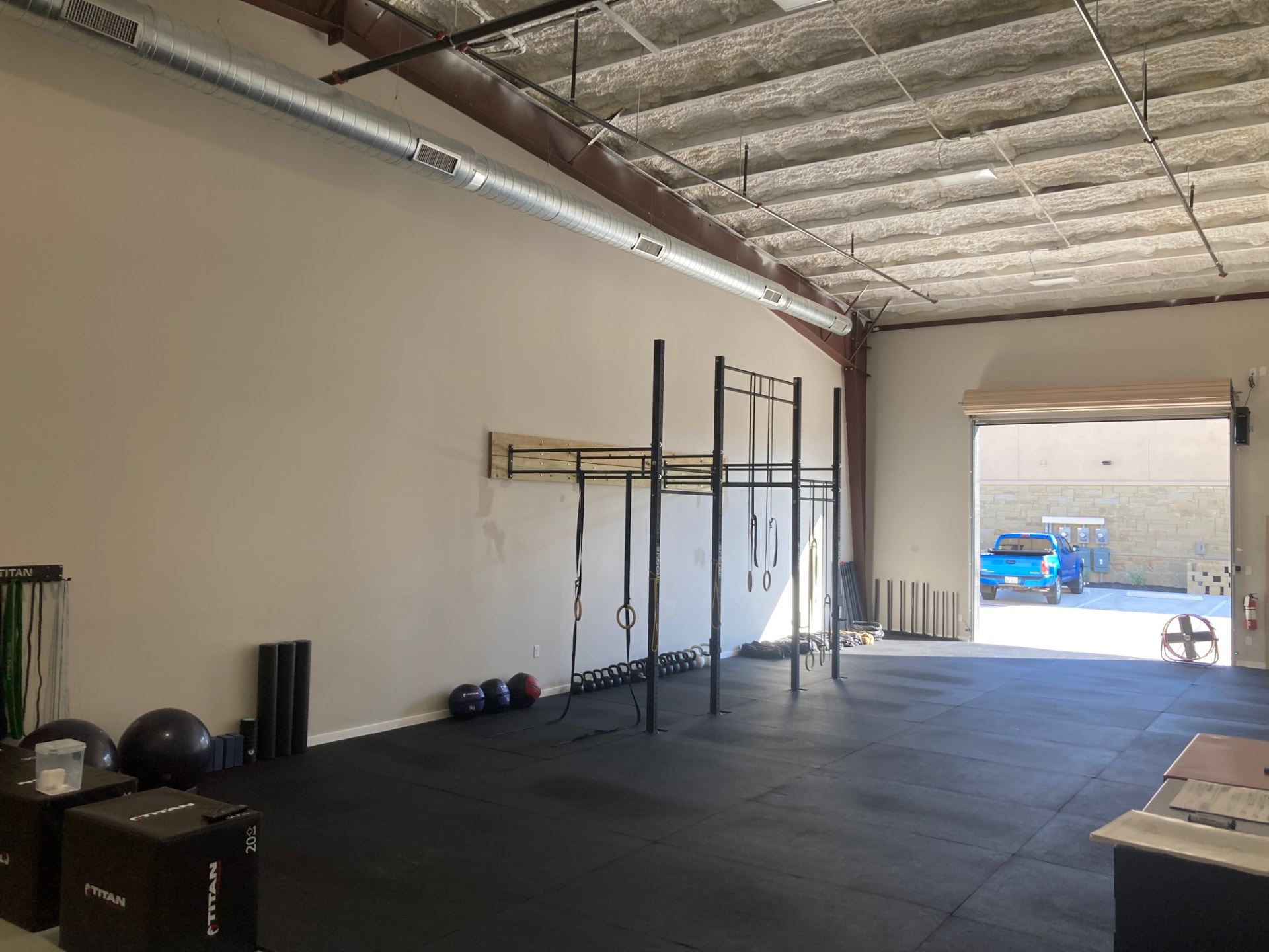 Open training floor with the rig, kettlebells and roll-up door at Liberty Bells in Leander, TX
